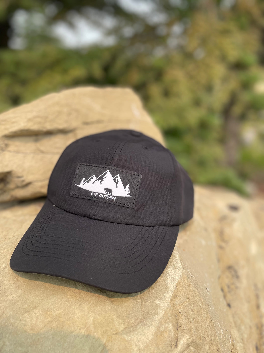 black athletic hat with black and white gtf outside logo. gtfo. logo with bear, trees and mountains