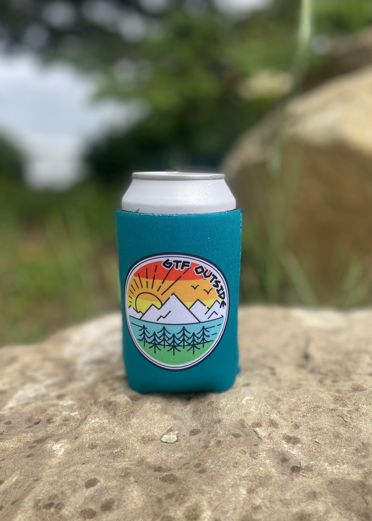 teal koozie with gtf outside logo. sunrise logo with sun, mountains and tree. gtfo.