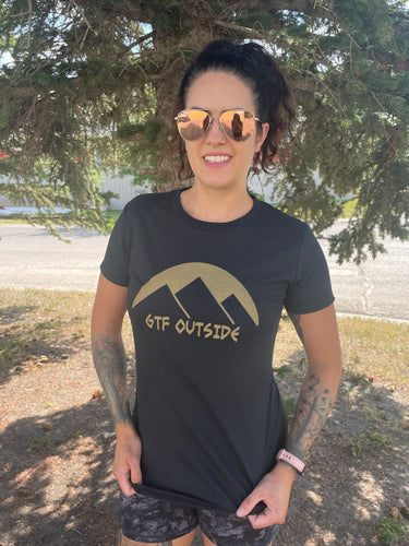 ladies black tee with gold gtf outside logo with sun and mountains. gtf outside. gtfo. ladies shirt.